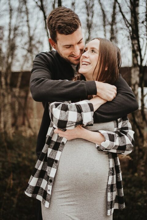 lachende zukünftige eltern bei babybauchshooting die sich auf ihr baby freuen